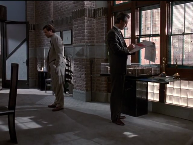 Michael and Miles in spacious upper office, with glass-brick windowpanes near floor, angled mesh panels on far door, exposed brick
